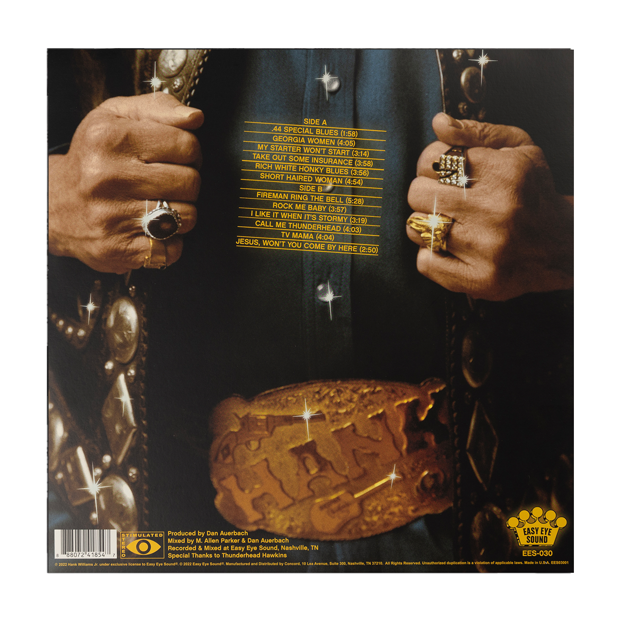 Album cover featuring hands wearing multiple rings and a golden object resembling a crown or burger.